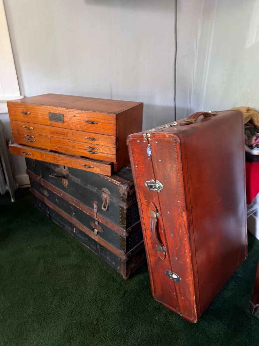 Vintage wooden trunks, leather suitcase, and wooden drawer chest at the Caldwell estate sale